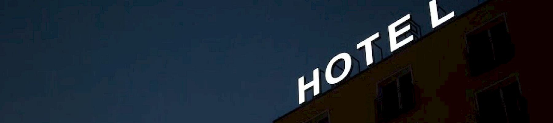 A building with a bright white "HOTEL" sign against a dark sky background, partial view of the facade.