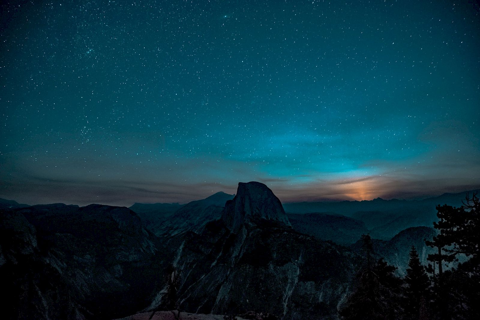A starry night sky over a mountain landscape, with a bright moon rising in the background, creating a serene and breathtaking view.