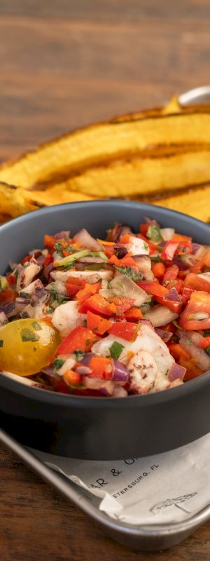 A bowl of fresh chopped salad with tomatoes, onions, cucumber and herbs, with tortilla chips beside it.