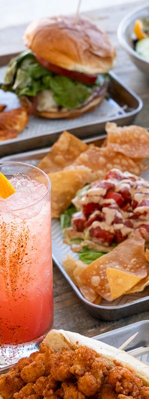 A spread of breakfast and lunch items: assorted plates with pancakes, fried eggs, salad, fruit, and beverages served on a table.