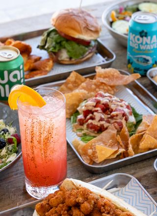 A spread of breakfast and lunch items: assorted plates with pancakes, fried eggs, salad, fruit, and beverages served on a table.