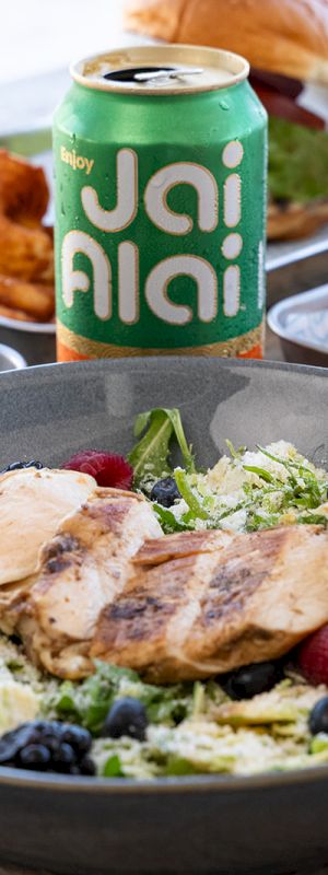A colorful plate of food with salad and toppings, a JAI? beverage can, and bright background&mdash;tasty-looking and vibrant.