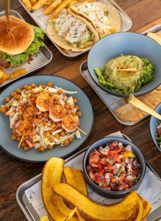 A spread of Mediterranean-style meals: falafel salad, hummus wraps, pita, fries, roasted squash, and fresh veggie sides.