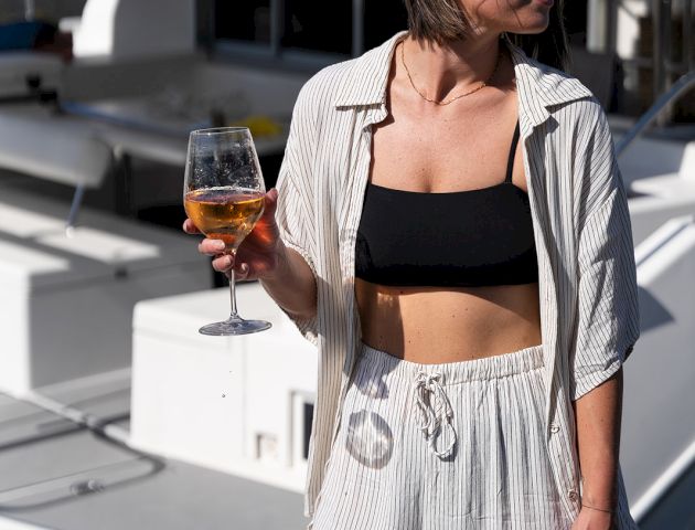A cropped street-style look featuring a black bralette, open striped shirt, and white shorts.