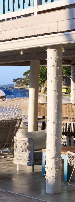 A storefront with a modern awning and outdoor seating; glass windows reflect the street, hinting at a cafe or shop beneath the covered area.